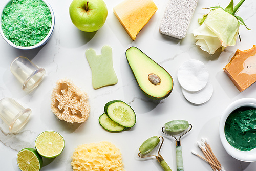 top view of natural beauty products and gadgets near fresh fruits and vegetables on marble surface