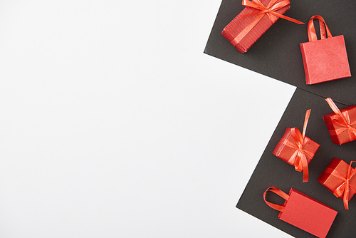 top view of red gift boxes and shopping bags on white and black background with copy space