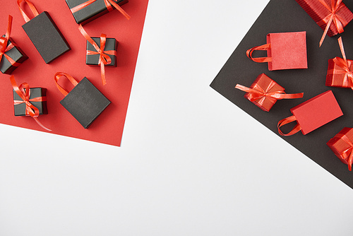 top view of decorative gift boxes and shopping bags on red, white and black background with copy space