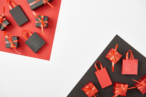 top view of decorative gift boxes and shopping bags on red, white and black background with copy space