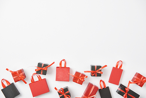 top view of black and red presents and shopping bags on white background with copy space