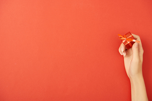 cropped view of woman holding gift box on red background with copy space