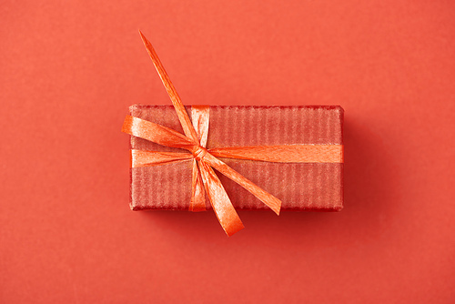 top view of gift box with bow and ribbon on red background