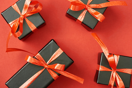 top view of black gift boxes with bows and ribbons on red background