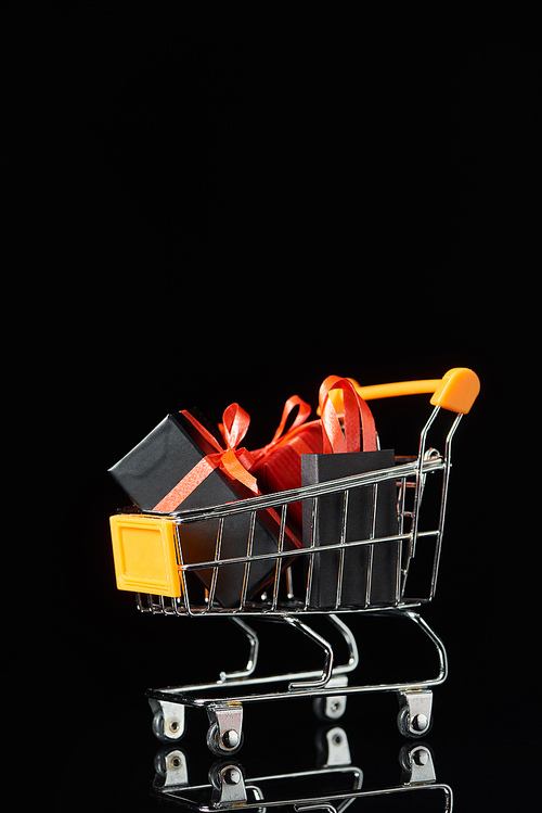 small gifts and shopping bag in decorative trolley isolated on black