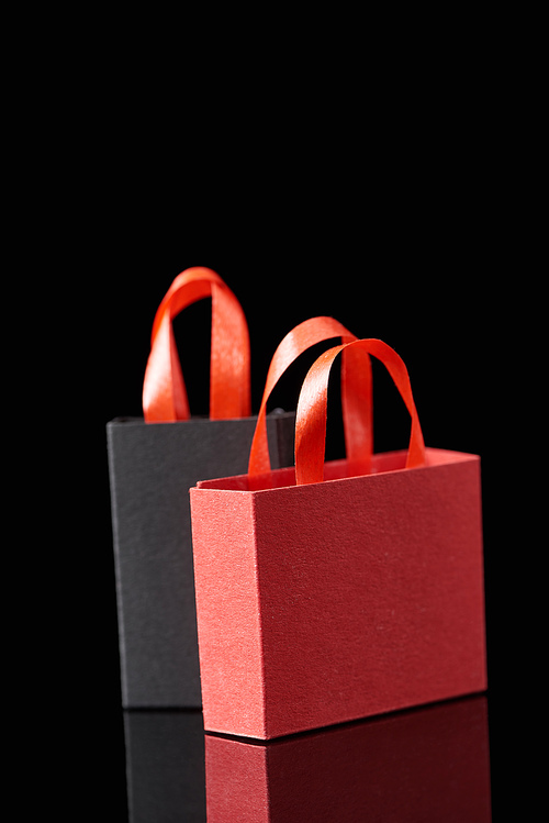 paper shopping bags with red handles isolated on black
