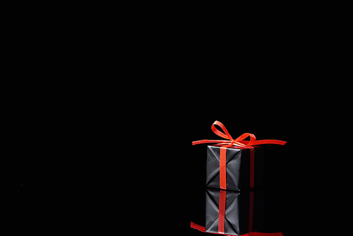 black decorative gift with red ribbon isolated on black