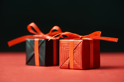 selective focus of gift boxes with red ribbons isolated on black