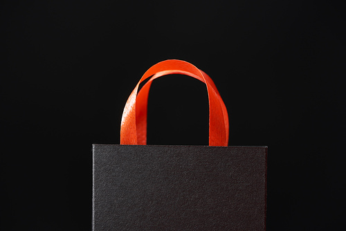 black shopping bag with red handle isolated on black