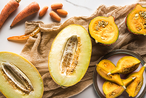 top view of melon halves, pumpkin, carrots and zucchini on canvas