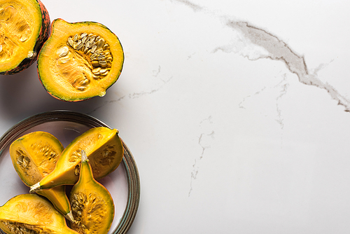 top view of plate with ripe pumpkin pieces on marble surface