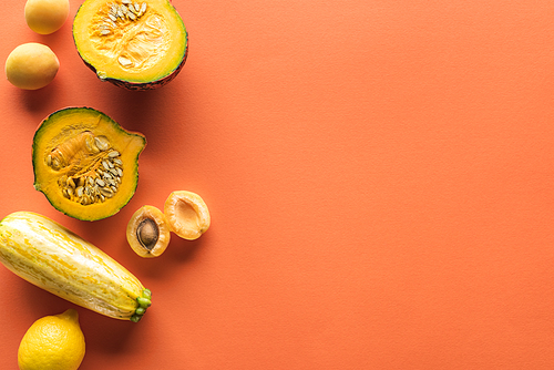 top view of yellow fruits and vegetables on orange background with copy space