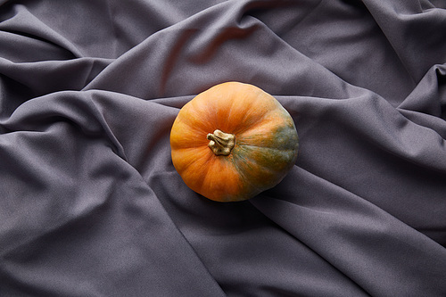 ripe whole colorful pumpkin on grey cloth