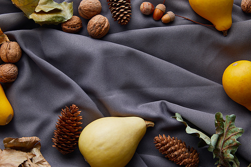 top view of ripe pumpkins and autumnal decor on grey cloth with copy space