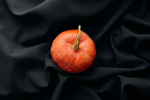 top view of ripe whole colorful pumpkin on black cloth