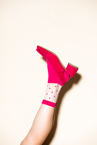 cropped view of female leg in pink retro socks and shoes on beige background