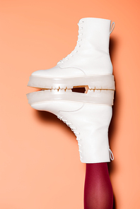 cropped view of female leg in red tights and boots on peach background