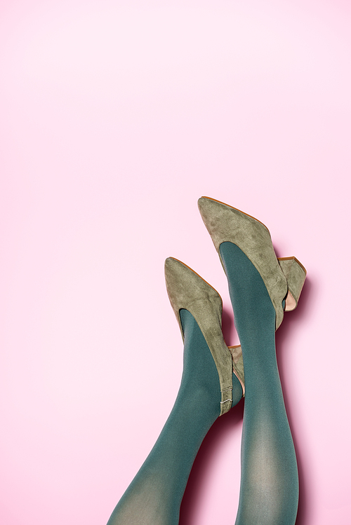 cropped view of female legs in green tights and retro shoes on lilac background