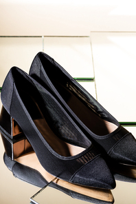 elegant black heeled shoes on mirror surface