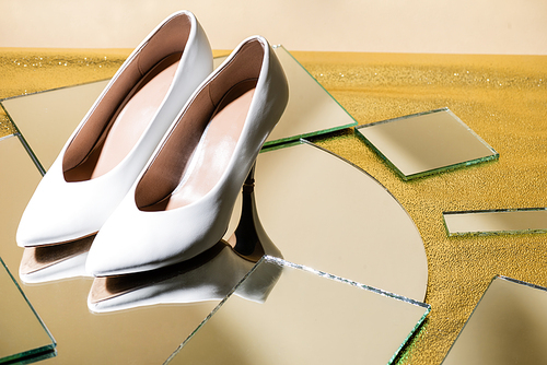 elegant white heeled shoes on mirror surface