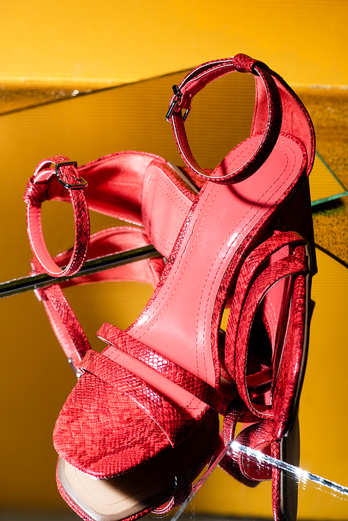 pair of elegant pink snakeskin heeled sandals on mirror surface