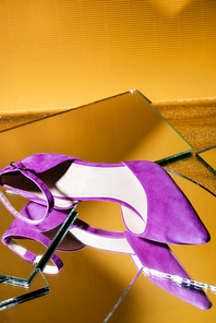 elegant violet suede heeled shoe on mirror surface on yellow background