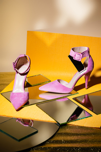 elegant violet suede heeled shoes on mirror and yellow paper