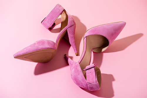 pair of elegant suede heeled shoes on pink background