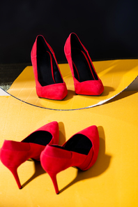 elegant red suede heeled shoes near mirror on yellow surface