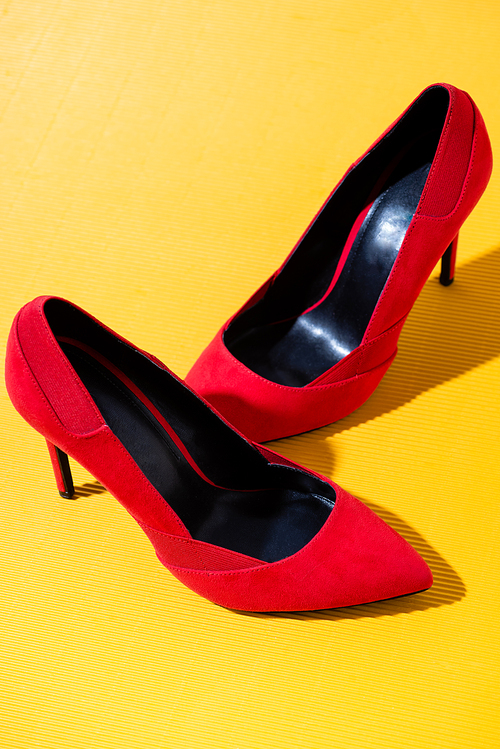 elegant red suede heeled shoes on yellow background