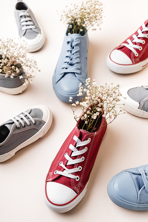casual sneakers and wildflowers on white background