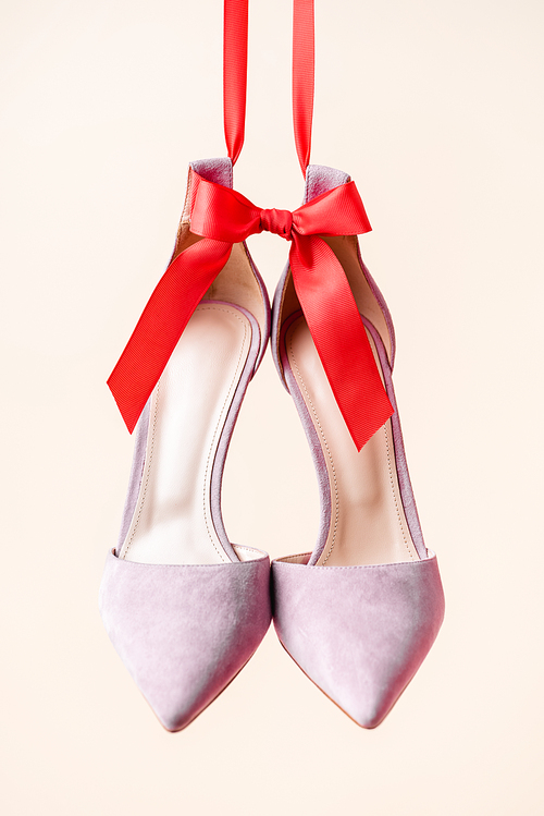 lilac suede heeled shoes with red bow isolated on beige