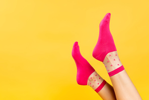 Cropped view of female legs in pink socks isolated on yellow
