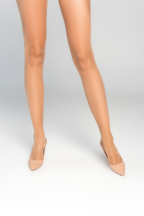 Cropped view of female legs in beige tights and shoes