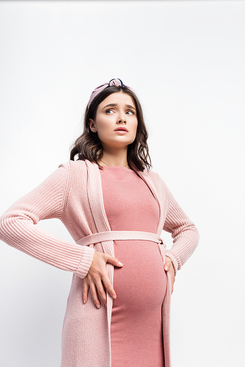 worried pregnant woman in headband touching belly and looking away isolated on white