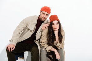 trendy man in beanie hat leaning on brunette woman on white