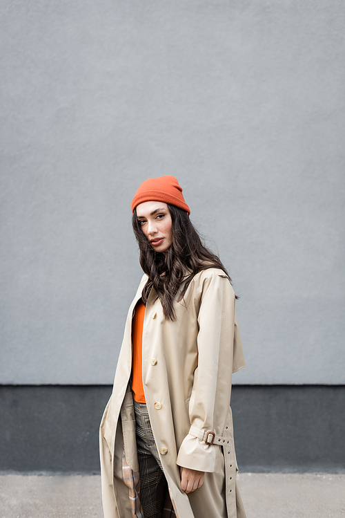 young trendy woman in trench coat and beanie hat 