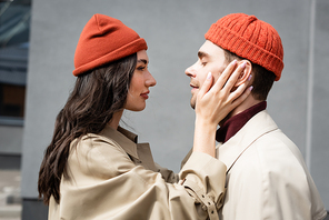 side view of trendy woman touching man in beanie hat