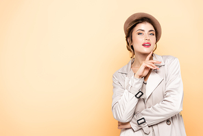 sensual woman in stylish trench coat and beret  on peach