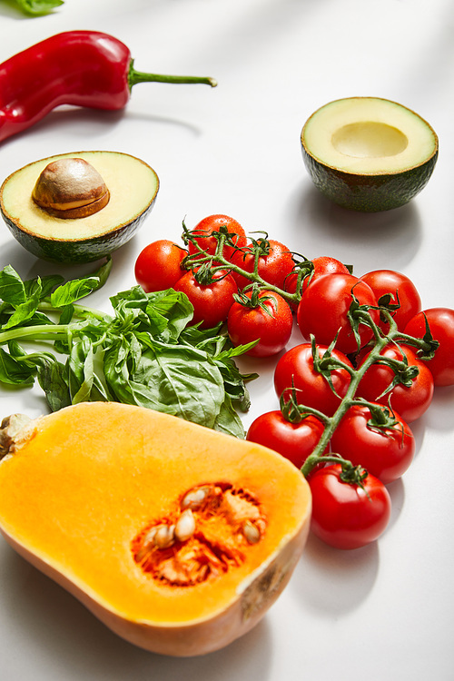 Pumpkin, cherry tomatoes, basil, chili pepper and avocado halves on white background