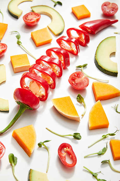 High angle view of cut vegetables, microgreens and avocado slices on white background