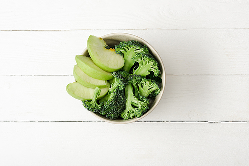 top view of fresh green apple and broccoli on white wooden surface