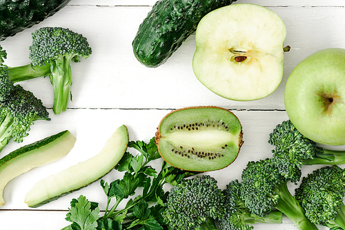 top view of fresh green fruits and vegetables on white wooden surface