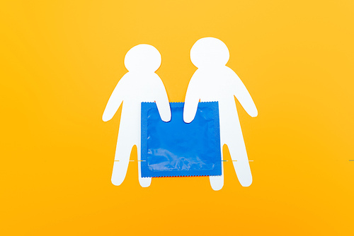 top view of paper people near blue condom isolated on orange