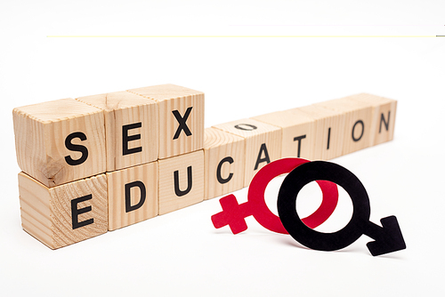 selective focus of wooden cubes with sex education lettering near gender symbols on white
