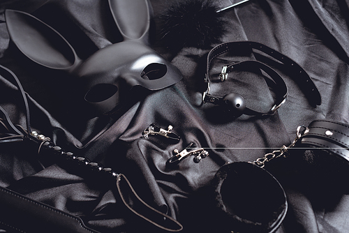 rabbit mask near sex toys on black silk fabric