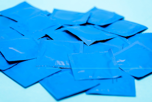 selective focus of packs with condoms isolated on blue
