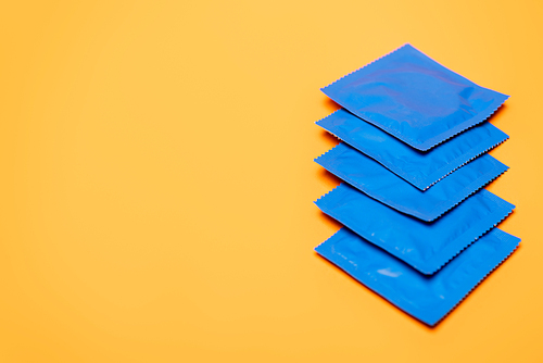 selective focus of blue packs with condoms isolated on orange with copy space