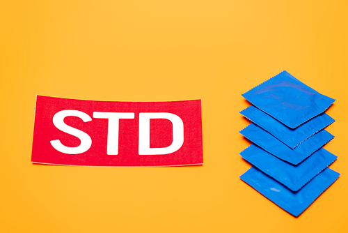 blue packs with condoms near std lettering isolated on orange