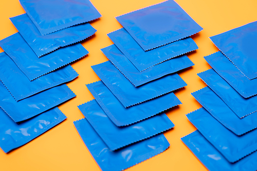 selective focus of blue packs with condoms isolated on orange